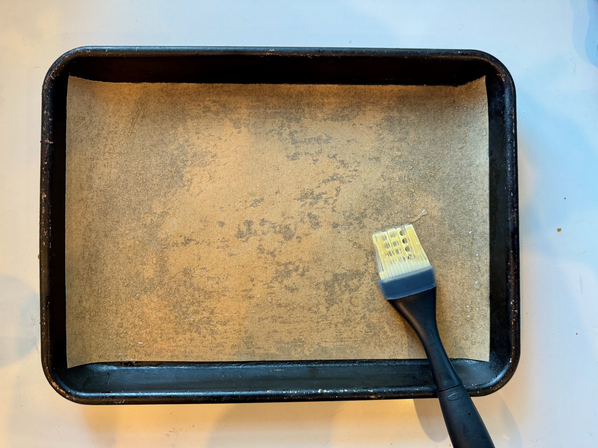 Greasing the parchment with a thin coating of oil helps to prevent the lye-soaked bagels from sticking.